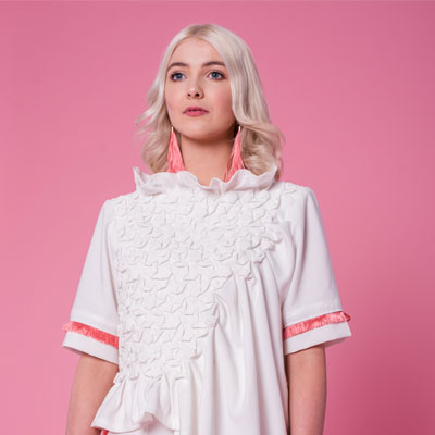 Part of the SS19 collection In Bloom, the Dahlia Top features a hand smocked front with asymmetrical drape and pink fringing. Paired with the Calla Trousers to complete the look; a pair of wide legged palazzo trousers with complimenting pink fringing and tie belt.
